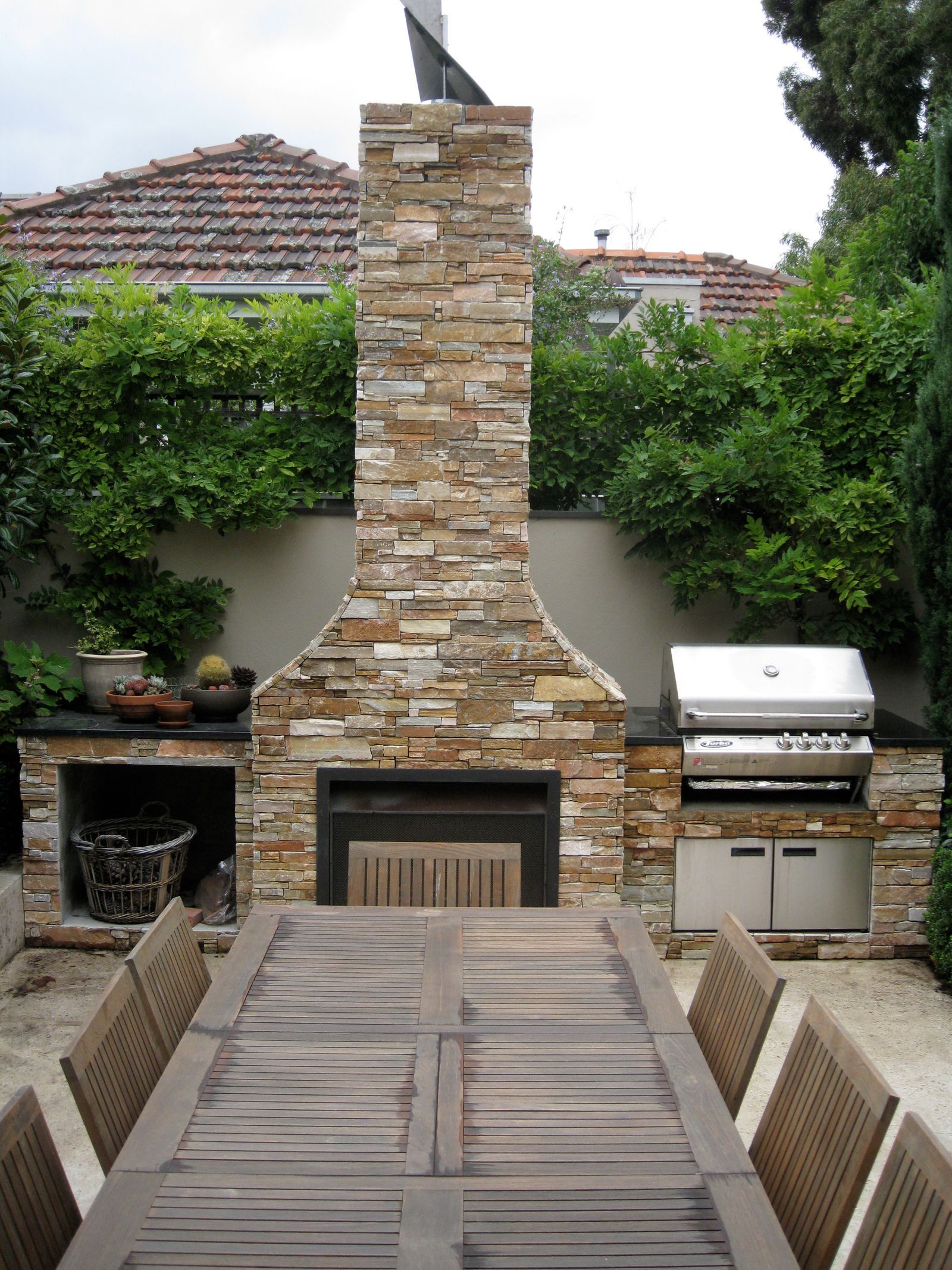 An outdoor fireplace terrace framed by lush greenery