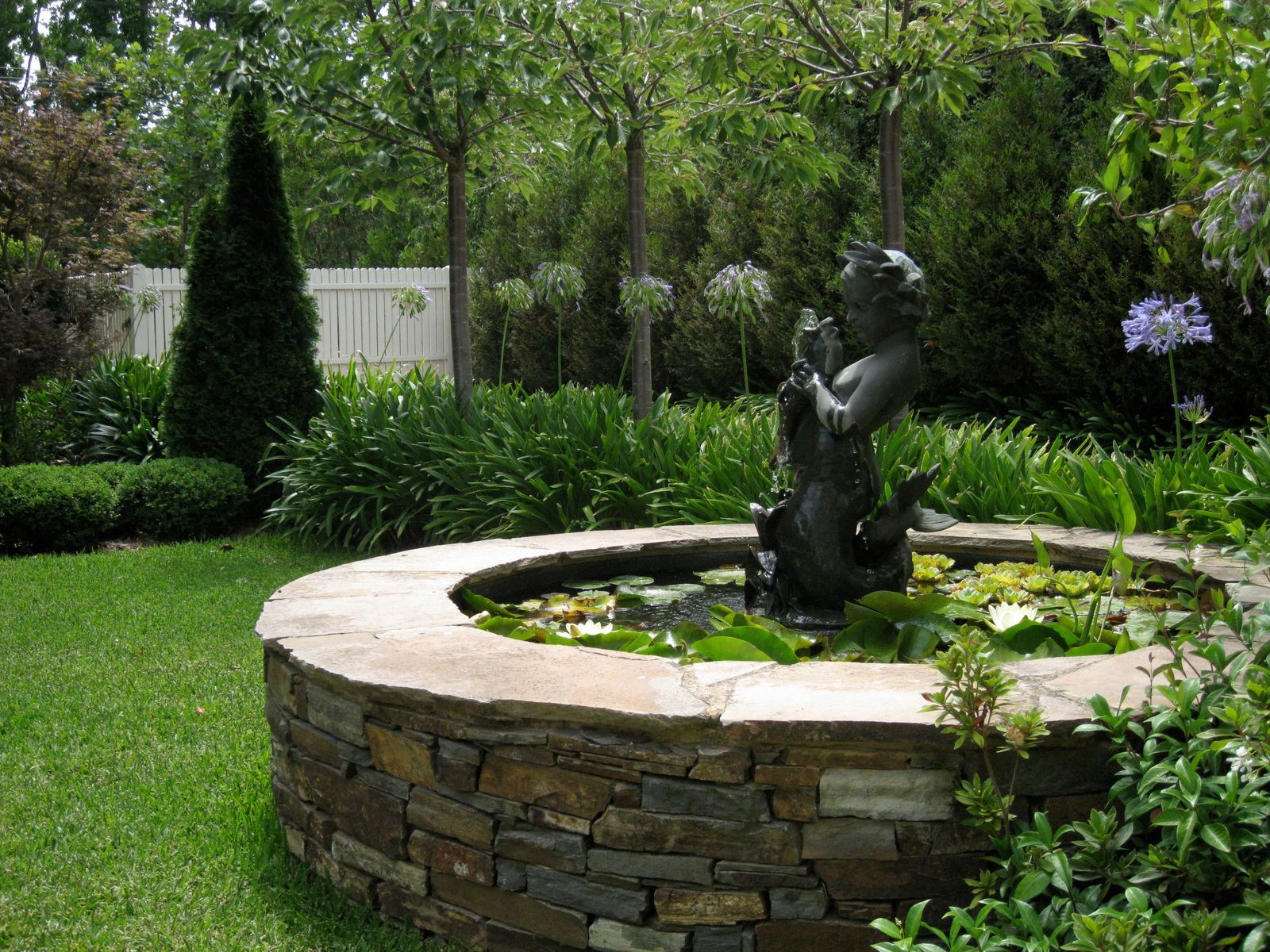 Stone fountain amid clipped hedging